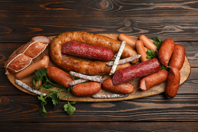 Different tasty sausages on wooden table, top view