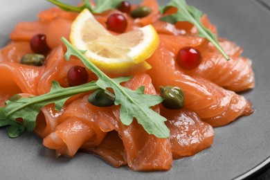 Salmon carpaccio with capers, cranberries, arugula and lemon on plate, closeup