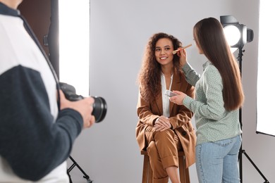 Professional photographer and makeup artist with model in studio