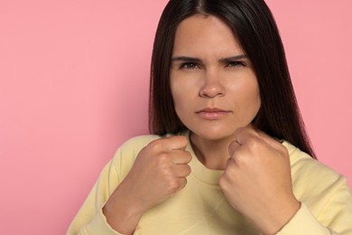 Young woman ready to fight on pink background, space for text