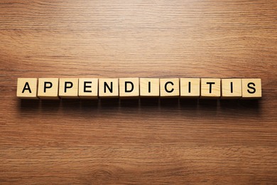 Photo of Word Appendicitis made of cubes with letters on wooden table, top view