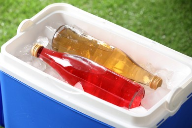 Blue plastic cool box with bottles and ice cubes outdoors