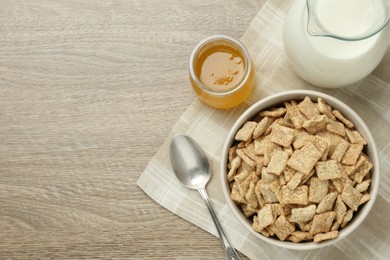 Bowl of sweet crispy breakfast cereal, milk and honey on wooden table, flat lay. Space for text