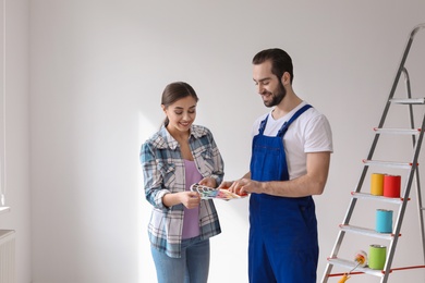 Male decorator and young woman with color palette indoors