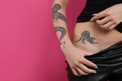 Woman with tattoos on body against pink background, closeup. Space for text