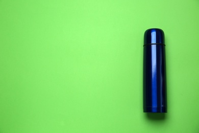 New modern thermos on green background, top view. Space for text