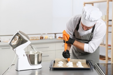 Pastry chef preparing meringues at table in kitchen