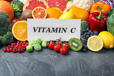 Different products and card with phrase VITAMIN C on grey table
