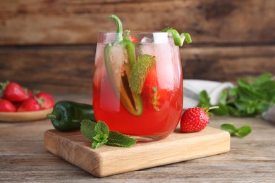 Photo of Spicy strawberry cocktail with jalapeno and mint on wooden table