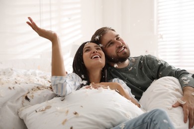 Happy young couple resting after fun pillow fight in bedroom