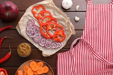 Photo of Flat lay composition with striped apron and different ingredients on wooden table