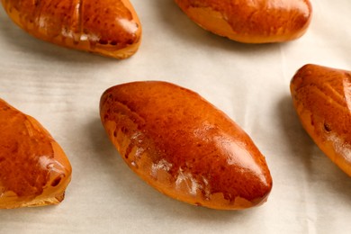 Delicious baked pirozhki on parchment paper, closeup