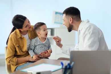 Mother and son visiting pediatrician in hospital. Doctor examining little boy