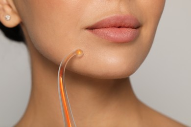 Photo of Woman using high frequency darsonval device on grey background, closeup