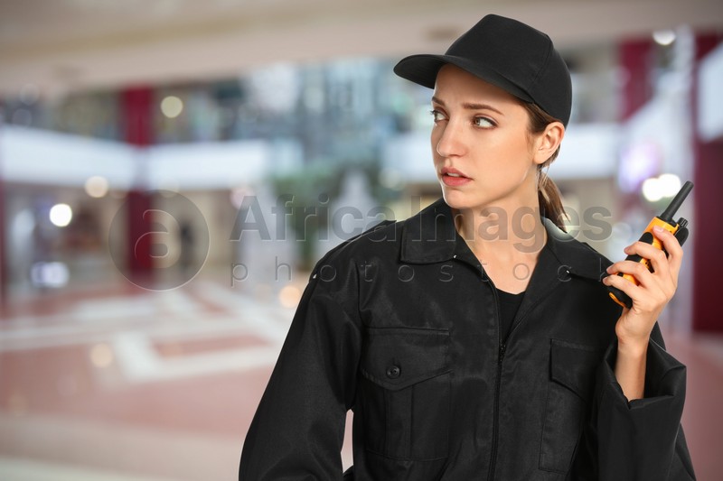 Female security guard wearing uniform using portable radio transmitter in shopping mall