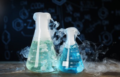 Photo of Laboratory glassware with colorful liquids and steam on wooden table against black background. Chemical reaction