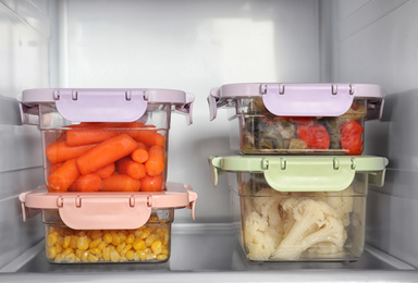 Lunchboxes with vegetables on shelf in refrigerator