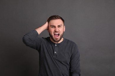 Portrait of emotional young man on grey background. Personality concept