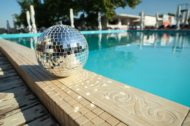 Shiny disco ball on edge of swimming pool. Party decor