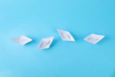 Handmade white paper boats on light blue, flat lay. background. Origami art