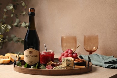 Bottle of red wine, glasses and delicious snacks on wooden table