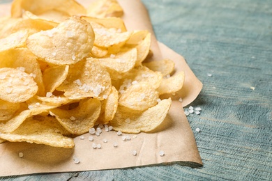Delicious crispy potato chips on table, closeup with space for text