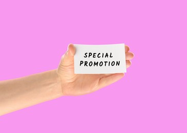 Woman holding card with text Special Promotion on pink background, closeup