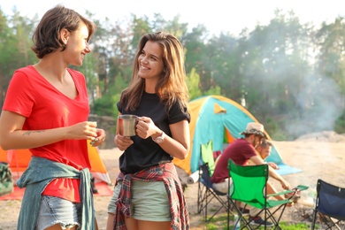 Young women near camping tent in wilderness