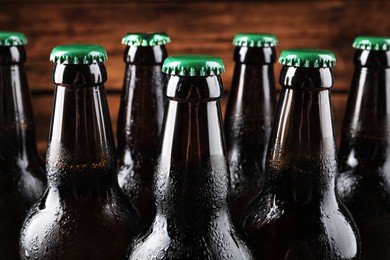 Photo of Many bottles of beer on wooden background, closeup