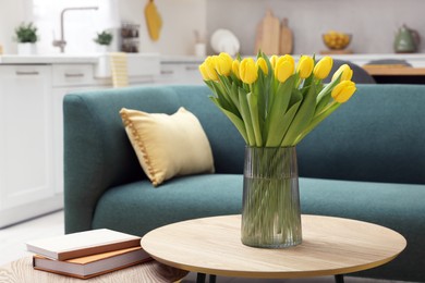 Photo of Spring interior. Bouquet of beautiful yellow tulips and books on wooden table in living room, space for text