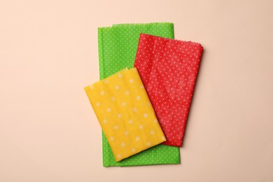 Colorful reusable beeswax food wraps on beige background, top view