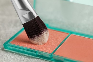 Photo of Mini blush palette with brush on grey table, closeup