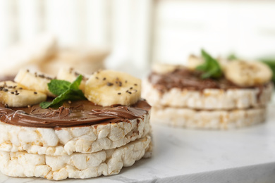 Puffed rice cakes with chocolate spread, banana and mint on board, closeup. Space for text