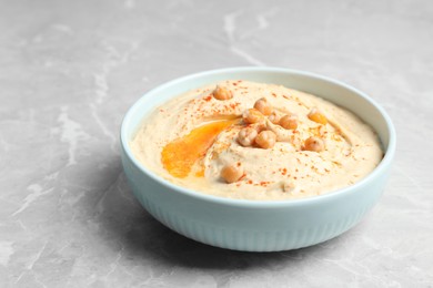Tasty hummus with garnish in bowl on light grey marble table