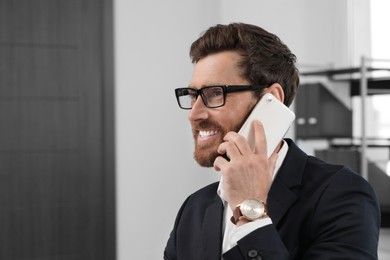 Happy bearded man talking on smartphone indoors