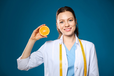Nutritionist with ripe orange on blue background