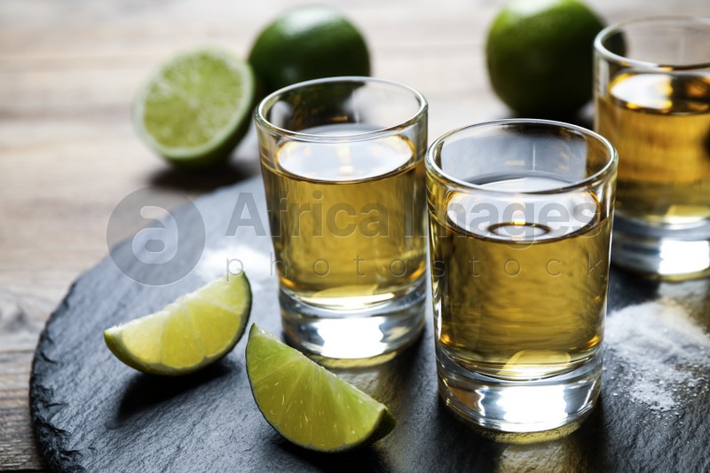 Mexican Tequila shots, lime slices and salt on wooden table