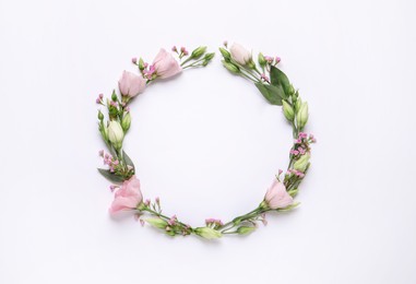 Wreath made of beautiful flowers and green leaves on white background, flat lay. Space for text