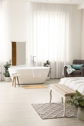 Stylish light apartment interior with white bathtub and bed