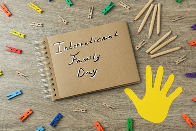 Photo of Happy Family Day. Flat lay composition with notebook, pencils and paper hand on wooden table