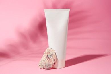 Photo of Cosmetic product, quartz gemstone and shadow of tropical leaf on pink background