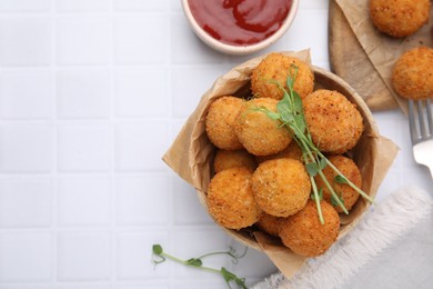 Photo of Bowl of delicious fried tofu balls with pea sprouts and sauce on white tiled table, flat lay. Space for text