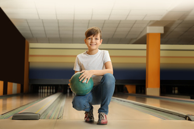 Preteen boy with ball in bowling club
