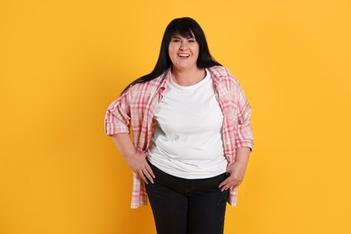 Beautiful overweight mature woman with charming smile on yellow background