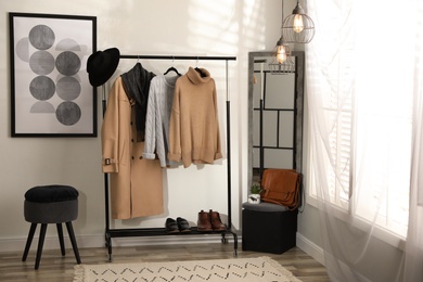Stylish warm clothes on rack in dressing room interior