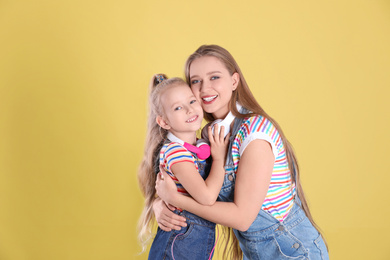 Happy mother and little daughter on yellow background