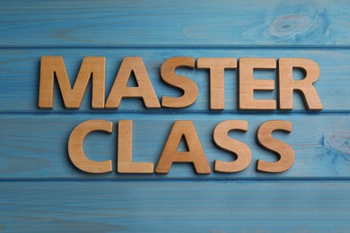 Words Master Class made of wooden letters on light blue table, flat lay