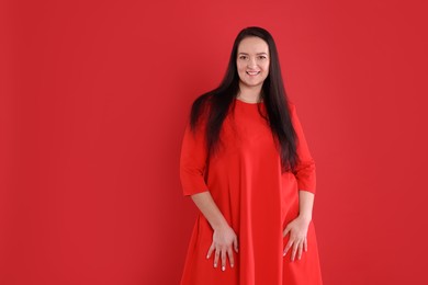 Beautiful overweight woman in dress on red background. Space for text