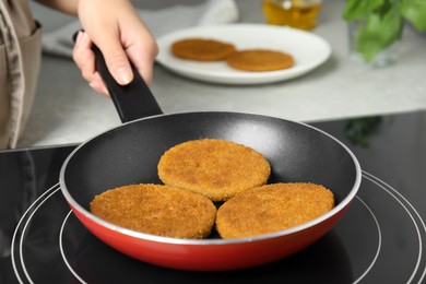 Woman cooking breaded cutlets in frying pan on stove, closeup
