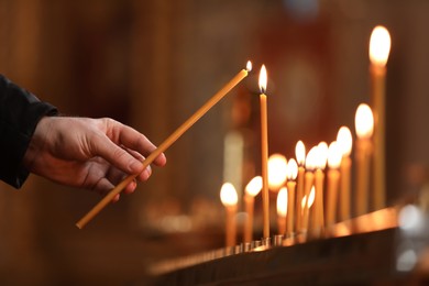 Man lighting candle near stand in church, closeup. Baptism ceremony